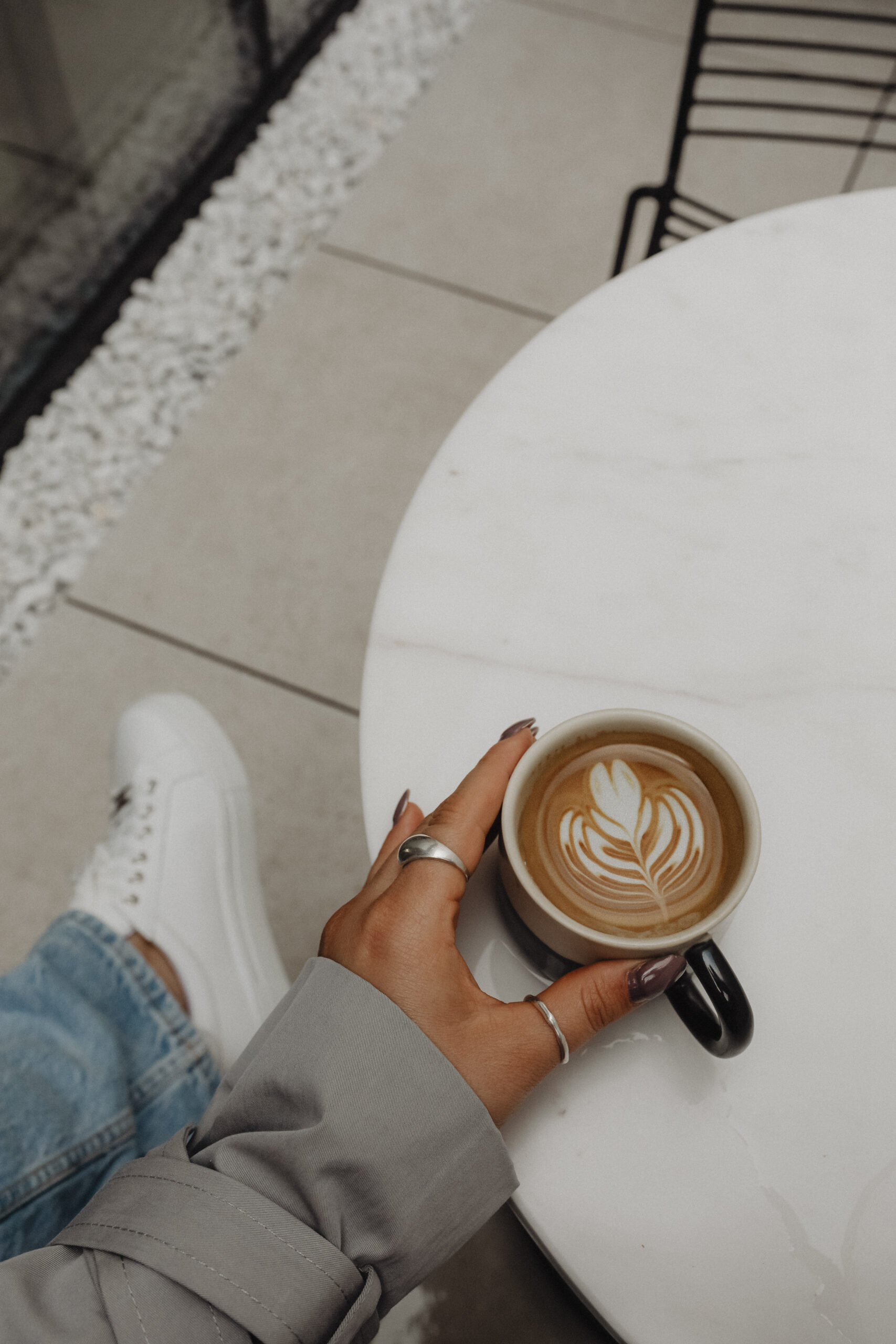 Woman sitting cross-legged in a chair holding a coffee mug, reflecting on how to choose the right therapist